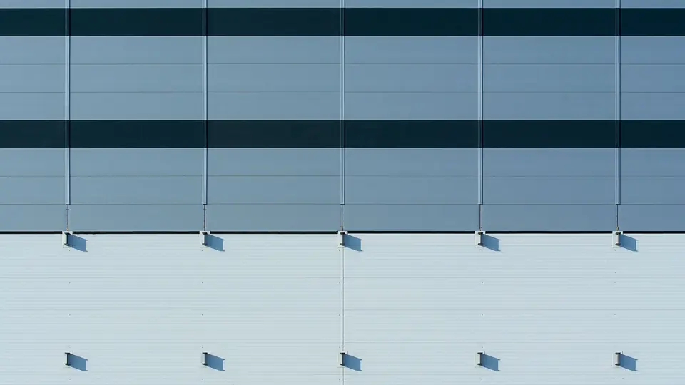 Close-up of flat insulated metal wall panels with fine horizontal ribbing and dark accent bands.